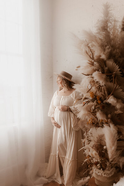 Pregnant mother looking down at her belly wearing an orange dress.