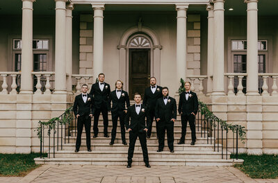 Wedding Photographer, groom and groomsmen standing on the steps of estate house