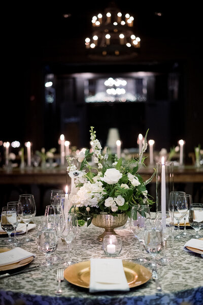 white flowers in vase in center of table with glasses surrounding