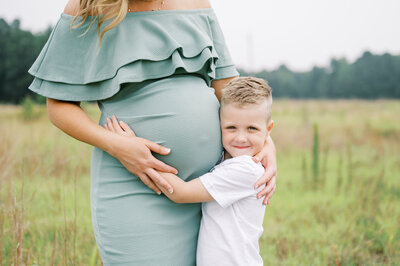 Little boy hugs mama's belly during outdoor family + maternity session in Raleigh NC