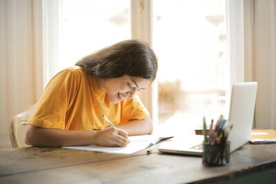 Woman in a yellow shirt smiling while preparing for her PA exams 
