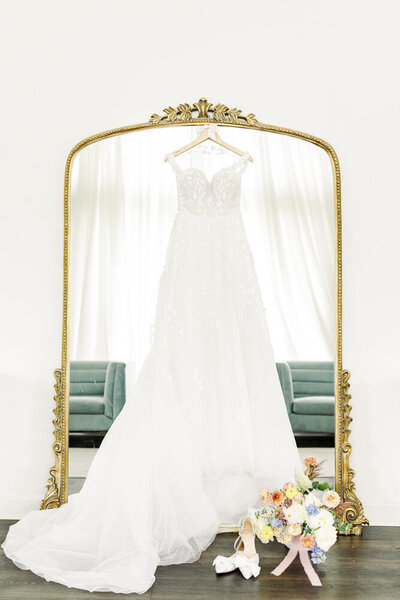 wedding dress hanging up in front of a mirror