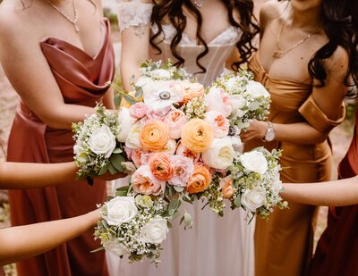 Detail shot of a pastel colored  bridal bouquet with oranges, blues, and purples laying on a rock.
