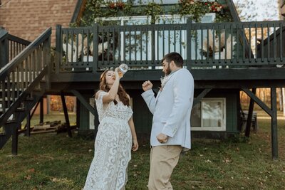 bride chugging wine groom celebrating in front of an a-frame cabin