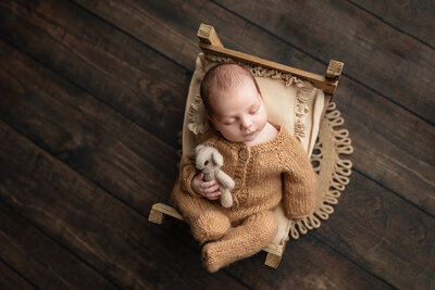 Studio newborn session of baby boy wearing gray overalls.