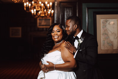 A black bride and groom embrace in their formal wedding venue