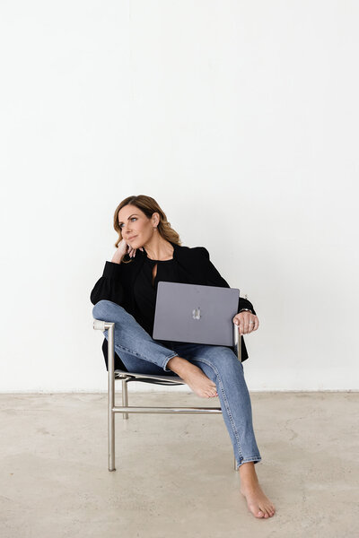 A wellness coach standing confidently in a vibrant pink suit during a personal branding photoshoot, showcasing her energetic and professional personality against a soft pink background