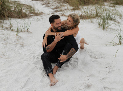 Intimate beach elopement couple laughing and embracing, candid and romantic moment for couples seeking relaxed, natural wedding photography