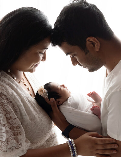mom and dad holding newborn baby girl swaddled in white wrap cleveland family photographer