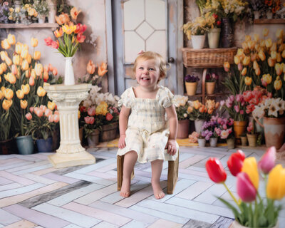Young girl in a spring dress smiles while surrounded by tulips