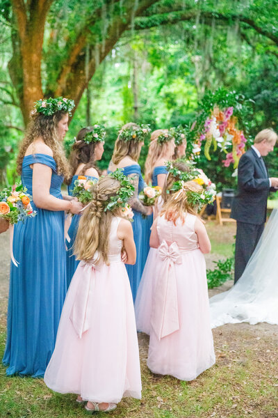 Wedding day ceremony while bridesmaids and flower girls look on photographed by Charleston wedding photographer Dana Cubbage.