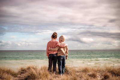 Brother and sister hugging each other as they look out over the ocean