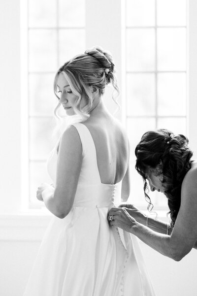 a woman helping a bride with her dress