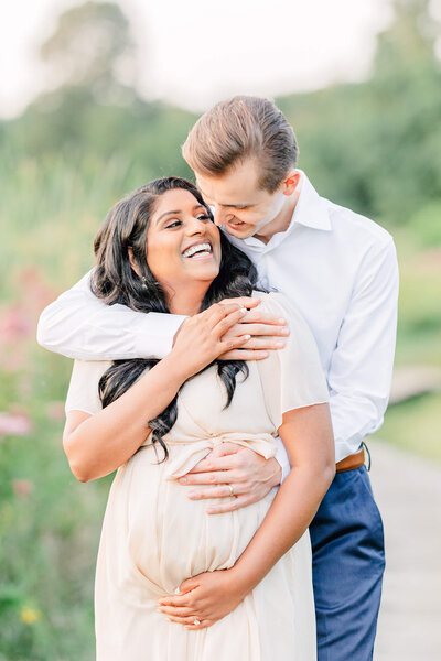 Husband embracing his pregnant, laughing wife during a Boston Area maternity photography session