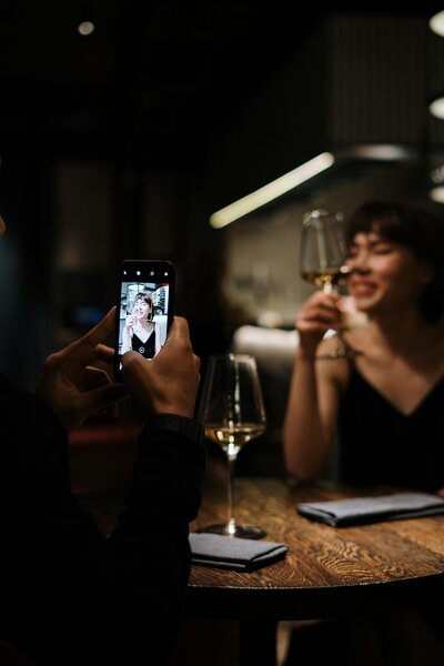 an iphone films a woman drinking wine in a bar