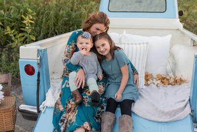 Mother and daughters cuddled together in back of vintage truck