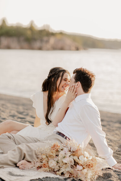 Bride and groom sitting on a beach on the North Shore during their intimate elopement in Minnesota