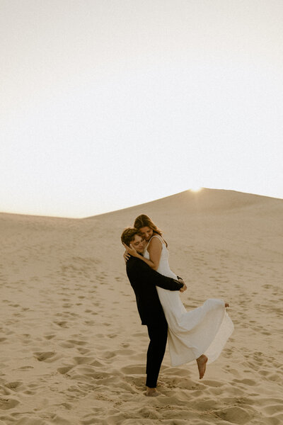 Groom picking up his bride at Silver Lake Sand Dunes