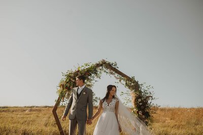 Couple posing in grass field in wedding attire