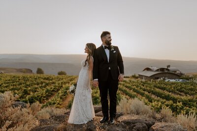 Couple Posed Back to Back with Vineyard in Background - Lindsey & Chip | Sagecliffe Resort & Inn Wedding Quincy Washington