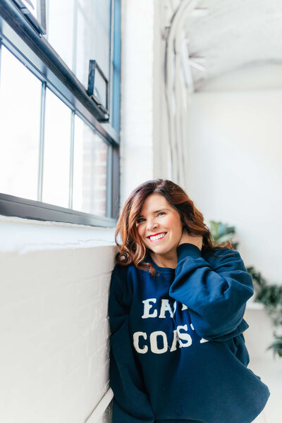 Kate wearing navy sweater that reads "East Coast"