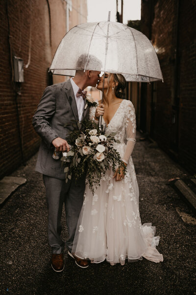 bride and groom kissing under umbrella