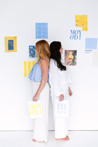 ALT: Grace standing looking at a wall with taped client project papers