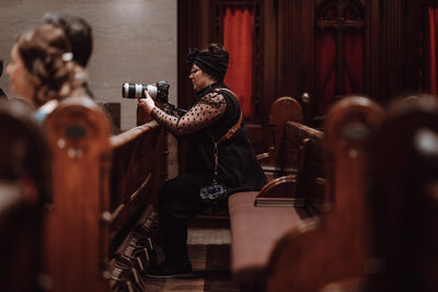 Kristen sits in a chapel pew to take a picture during a wedding ceremony