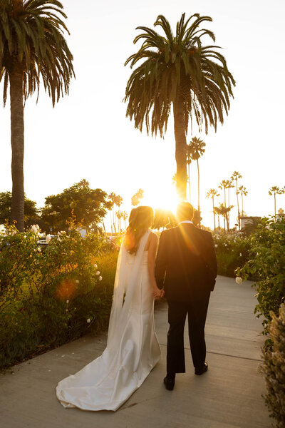a bride and groom walking into the sunset