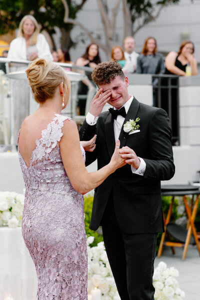 Groom wipes tears from his eyes as he dances with his mother at his wedding reception