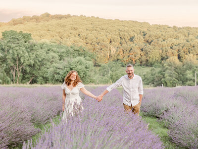 A couple holding hands walking through a lavender field