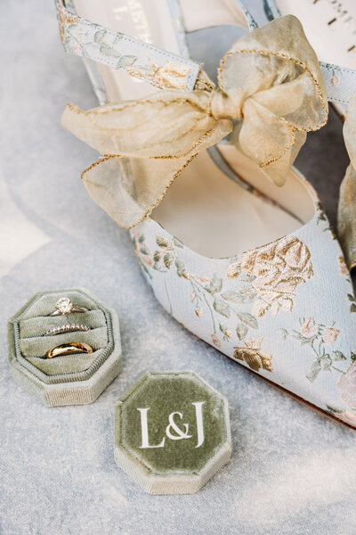 Close-up of wedding shoes, rings and jewelry displayed on a vintage table