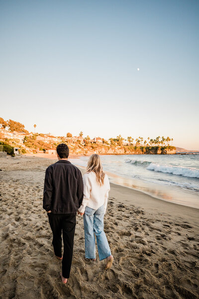 couple walking hand in hand cliff side in laguna