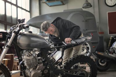 A middle-aged white man works on a motorcycle