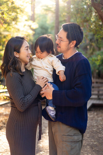 Parents holding toddler together in golden sunlight during Bay Area Mini Sessions - Ellobelle Photography