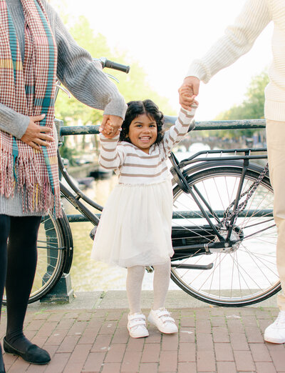 Toddler swings between parents on the Amsterdam Canals, near the Negen Straatjes.