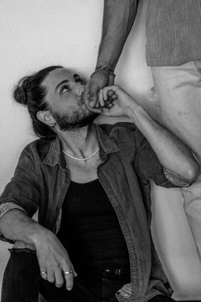 A man holds his partner's hand and kisses it.