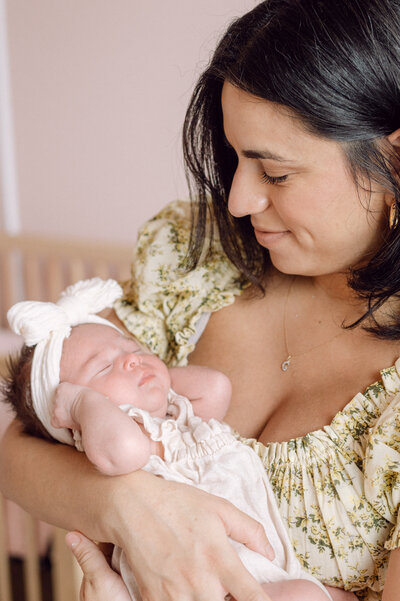 A mother lovingly holds her sleeping newborn baby in soft natural light during an in-home family photography session in Northern Virginia.
