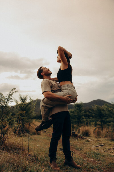 Playful couple camping in the hinterland jumping into each other captured by a Sunshine Coast photographer