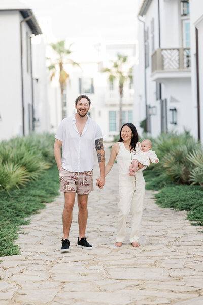 A couple holding hands while one holds a baby