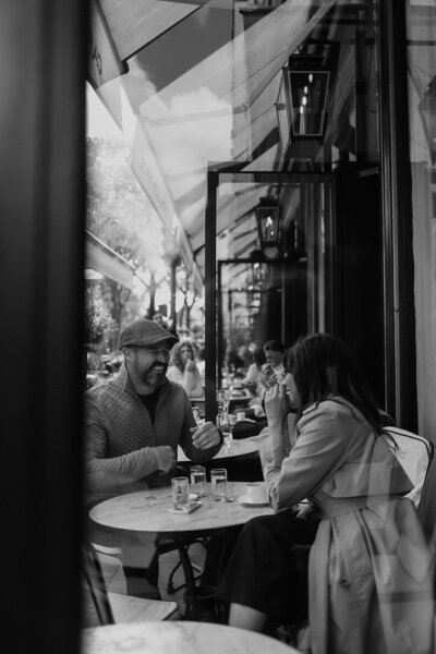 Black and white image of San Francisco Wedding Photographers Tony and Char sitting outside of a café