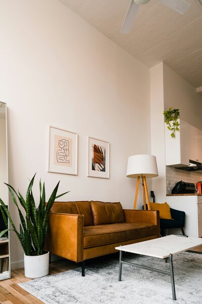Modern living room with a leather sofa, floor lamp, and artwork.