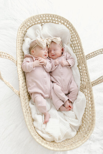Twin girls snuggled in basket and smiling in Indianapolis studio newborn photos