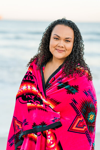 Lifestyle branding portrait of an artist on the beach, wrapped in a boho towel