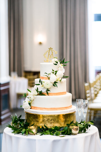 A stunning towered wedding cake with gold trim and the couples custom monogram cake topper