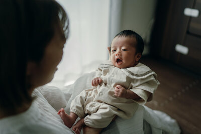 赤ちゃんを抱き上げて愛おしげに見つめているお母さん