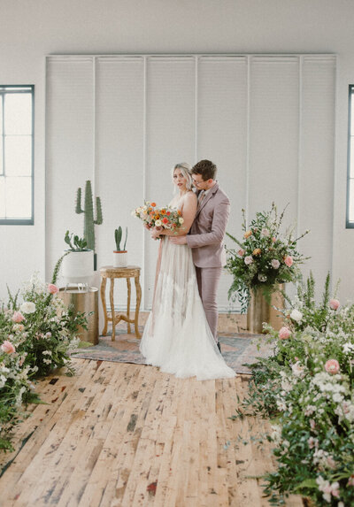 groom holding bride from behind with floral displays