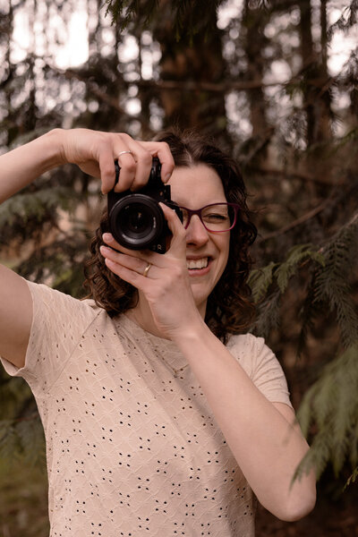 Fotografe heeft camera voor haar oog om een foto te maken in het bos.