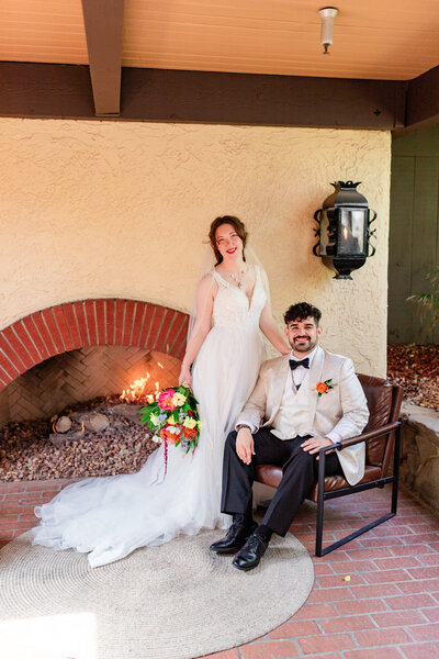 bride and groom pose next to fireplace