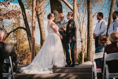 Reverend Peter Leidy officiates outdoor wedding ceremony with groom in military uniform